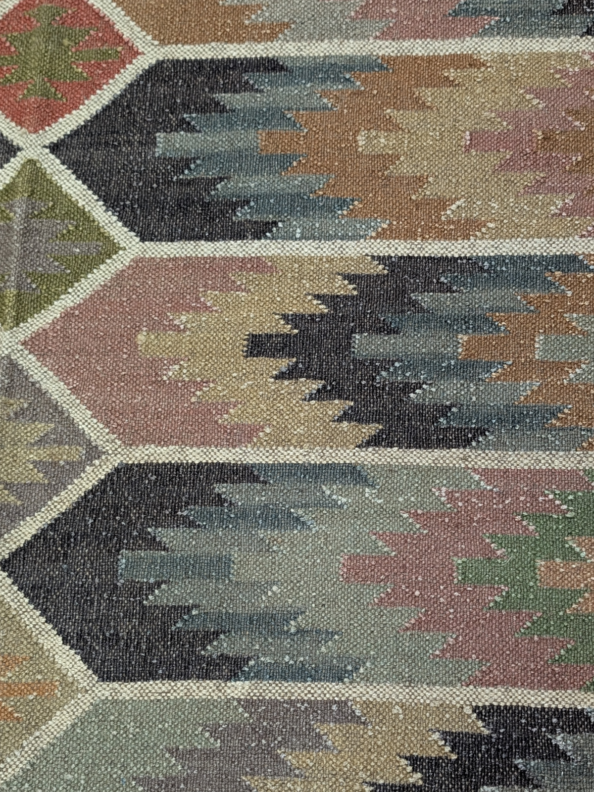 Inspired by the raw beauty of rugged landscapes, the Echoes of the Highlands Kilim Rug brings a sense of tranquility and timeless craftsmanship to your home. Handwoven by skilled artisans, this wool flatweave rug features a mesmerizing geometric design with earthy hues of sage green, terracotta, charcoal, soft beige, and muted blues, evoking the essence of misty highlands and rolling hills. Its intricate diamond motifs and horizontal patterns create a harmonious blend of tradition and modernity, making it a