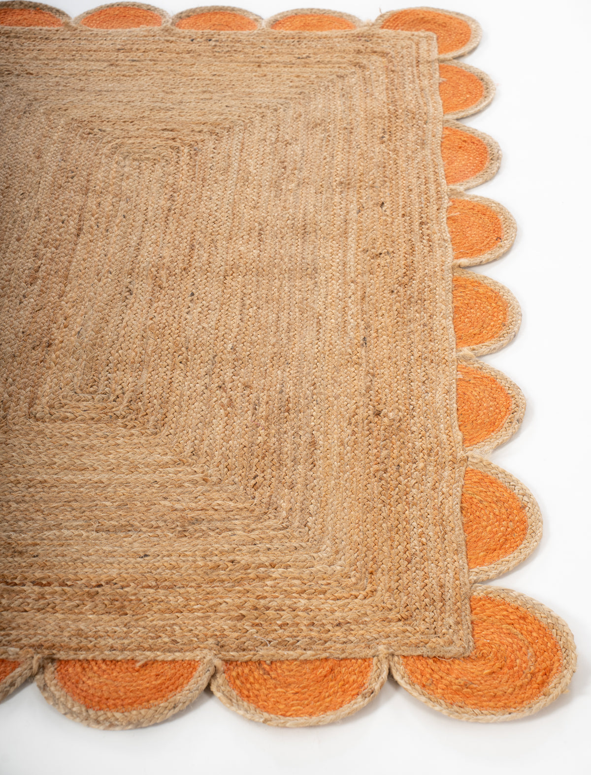 Kribi scalloped jute area rug-Orange jute rug styled in a living room interior