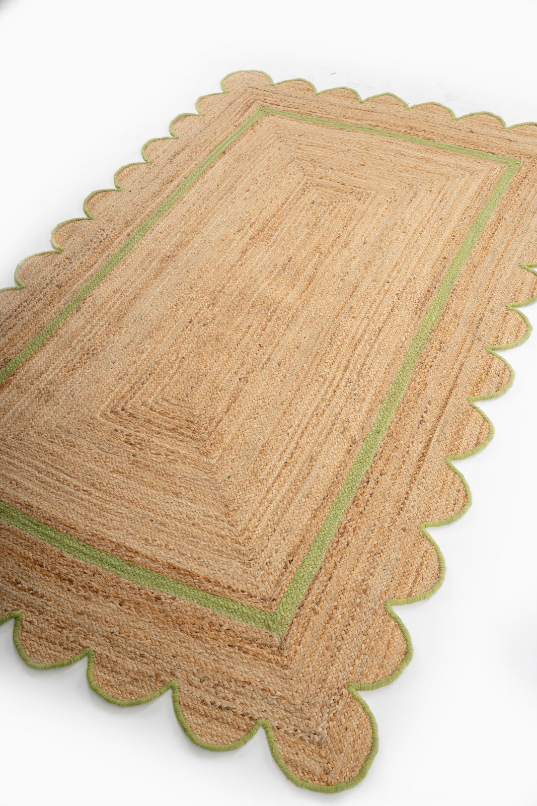 Moroni scalloped area rug-Leaf green cotton rug styled in a living room interior