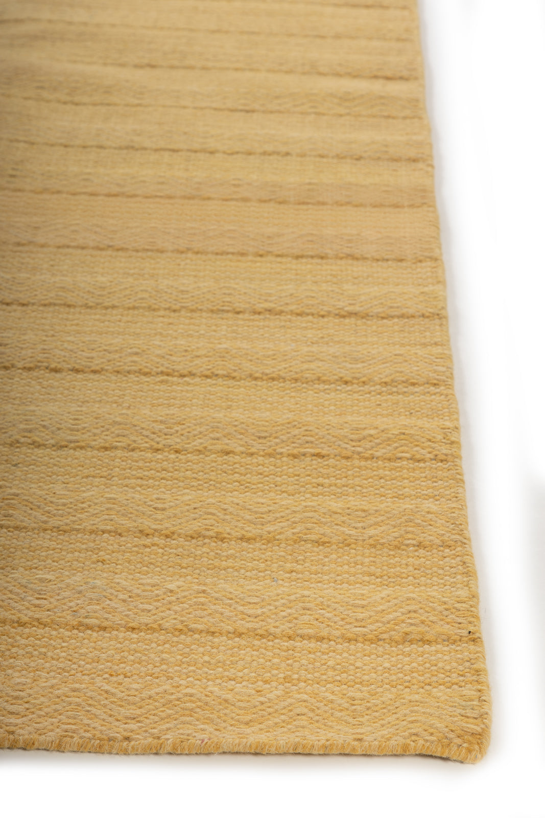 The Ochre Herringbone wool rug styled in a living room interior